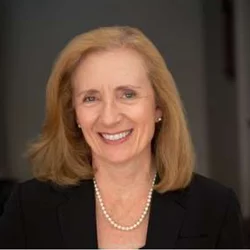 Carol Mangione is pictured here. She is smiling and has blonde hair wearing a black jacket